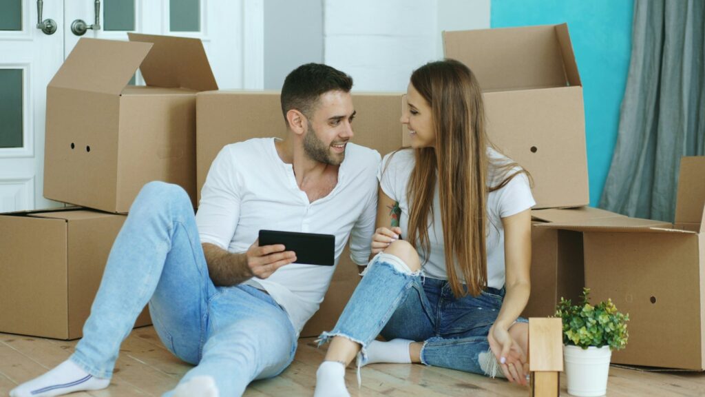 Couple with a tablet surrounded by moving boxes